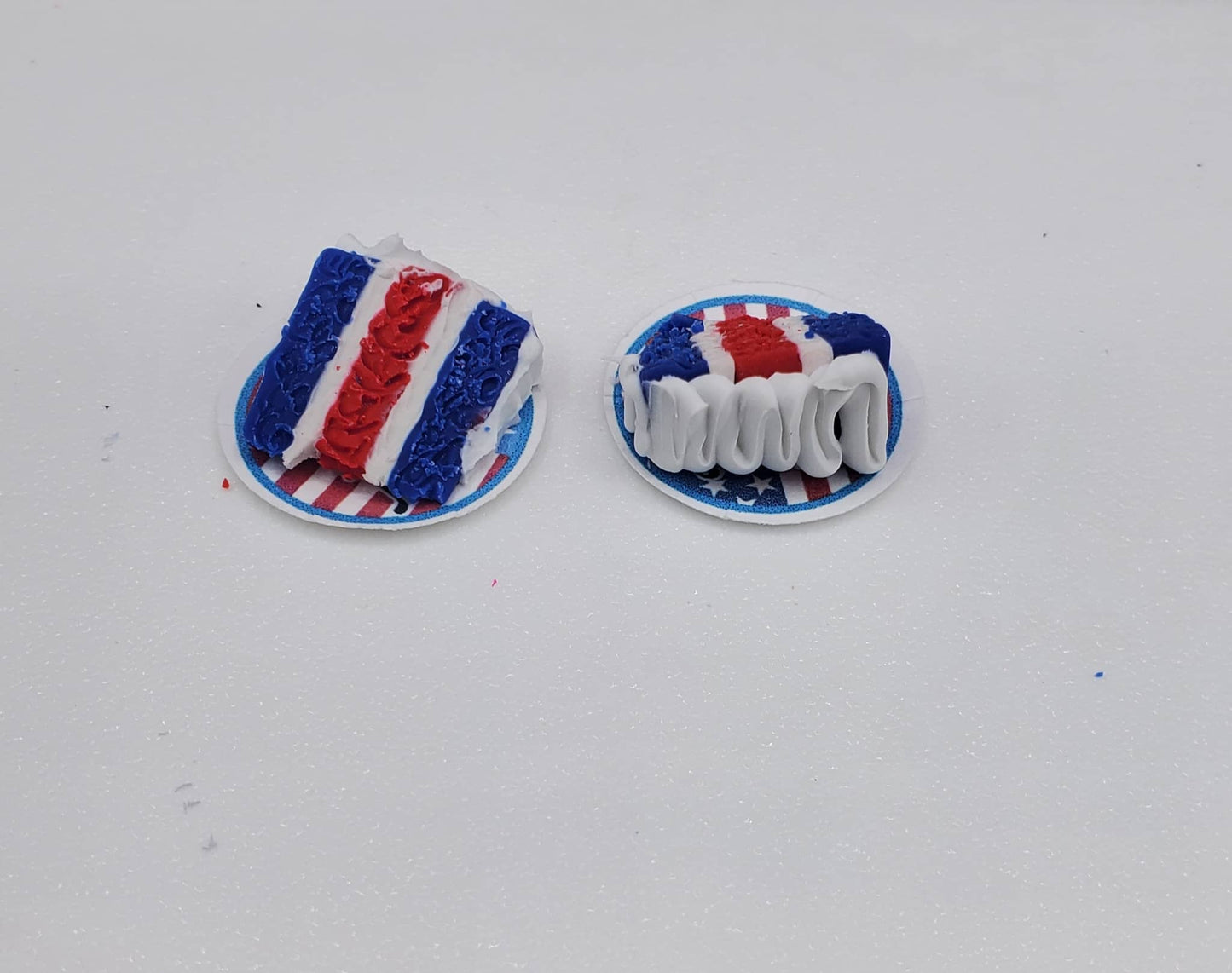 Two small decorative items resembling cakes with red, white, and blue icing on a white background.