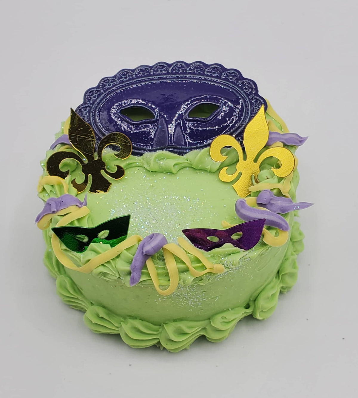 Chef Gina's Mardi Gras doll cake decorated with colorful masks and fleur-de-lis in green purple and yellow