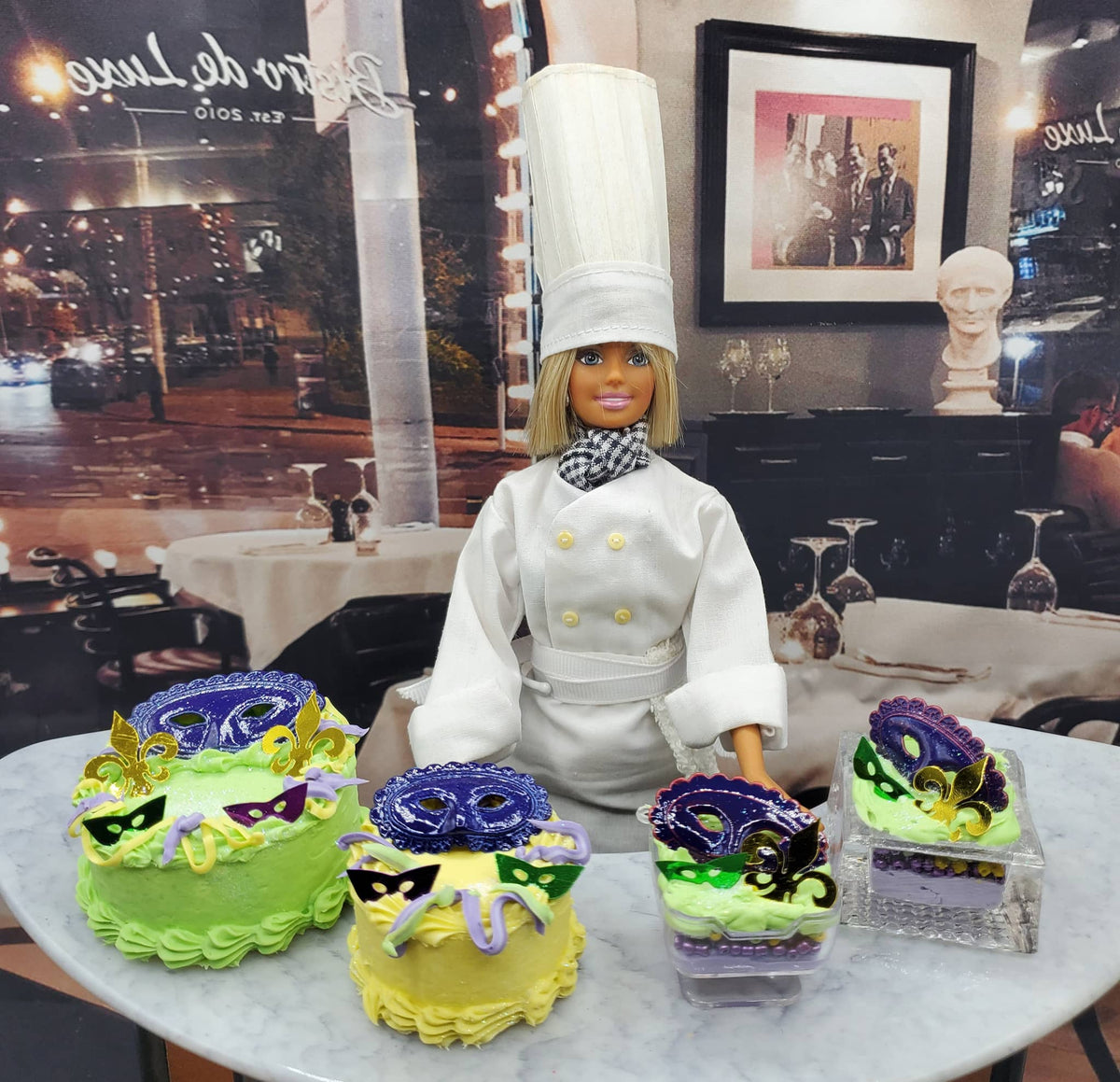Chef Gina's Mardi Gras doll cake displayed with small Mardi Gras themed cakes featuring colorful masks and festive decorations