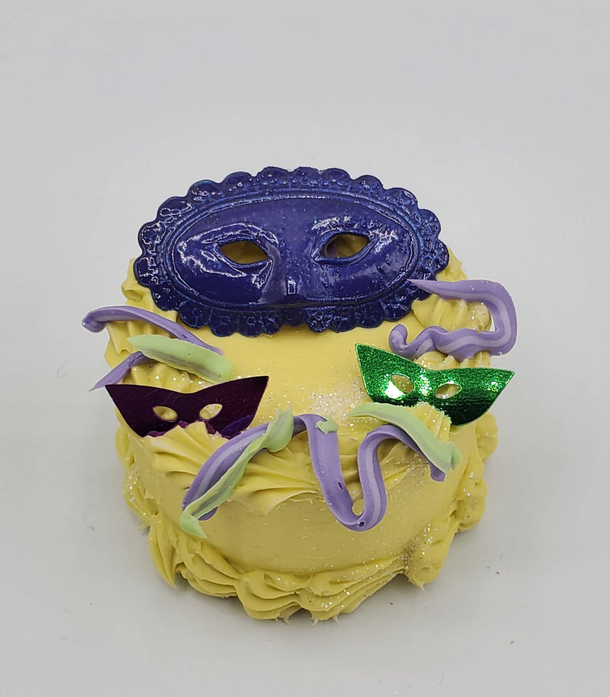 Chef Gina's Mardi Gras doll cake with yellow frosting and decorative purple and green masks