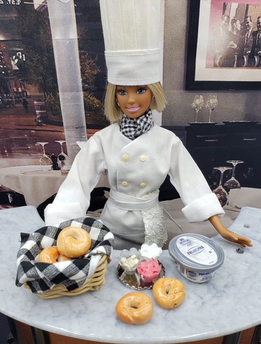 Chef Gina's Mini Food doll chef with a miniature bagel basket containing bagels on a marble table