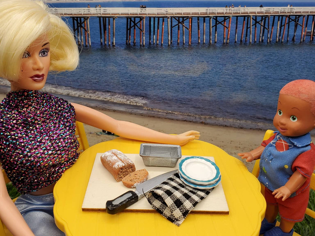 Chef Gina's miniature banana bread for dolls displayed on a picnic table by the beach