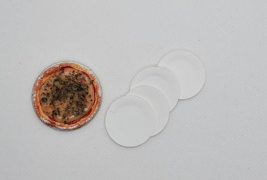 Chef Gina's miniature cheese pizza dollhouse accessory with four white paper plates on a light background
