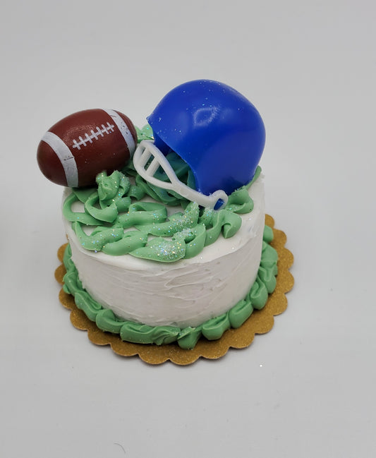 Chef Gina's miniature football cake with white frosting, green icing grass, blue helmet, and football decoration