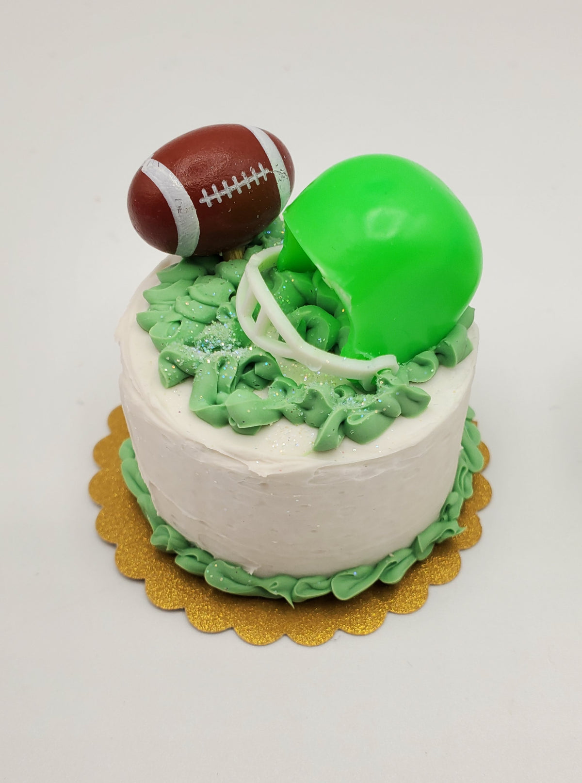 Chef Gina's miniature football cake with green helmet and brown football decorations on white frosting