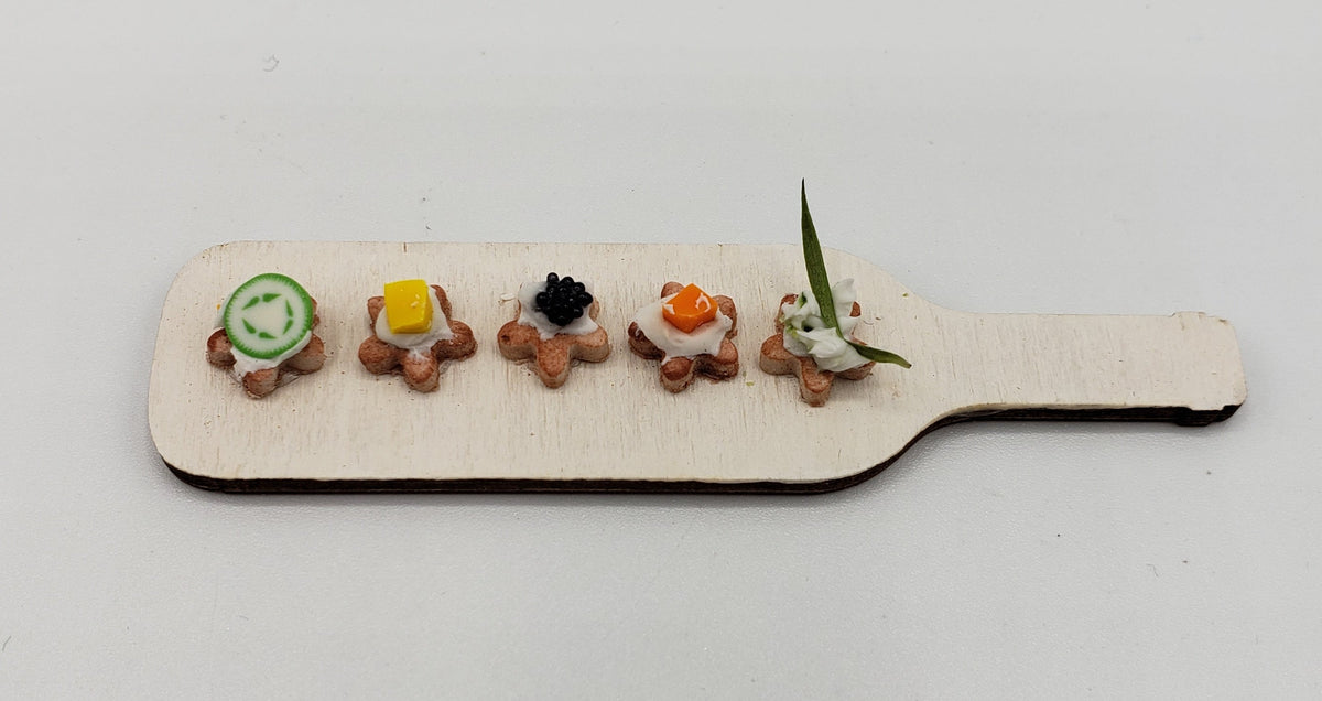 Chef Gina's miniature hors d'oeuvres platter with five assorted bite-sized appetizers on a wooden paddle