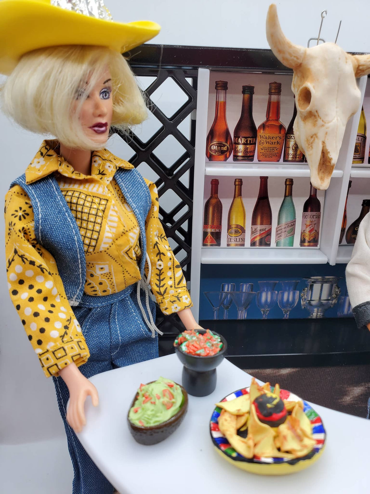Miniature salsa for dolls served with chips and guacamole held by a doll in cowboy outfit