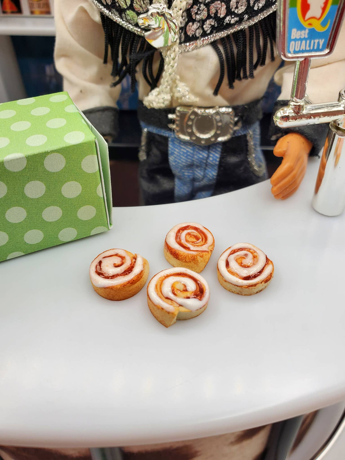 Miniature Texas cinnamon rolls for Fashion dolls displayed on a white surface with a green polka dot box nearby
