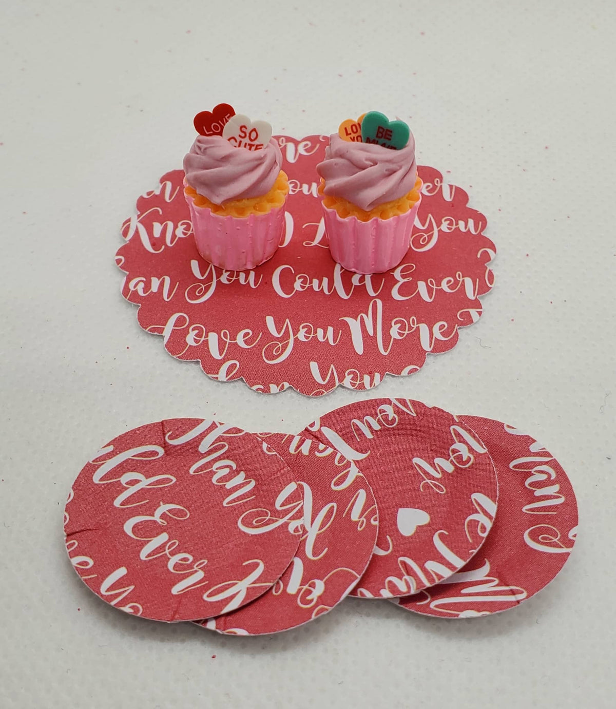 Chef Gina's miniature Valentine's cupcakes with pink frosting and heart toppers on red love-themed coasters