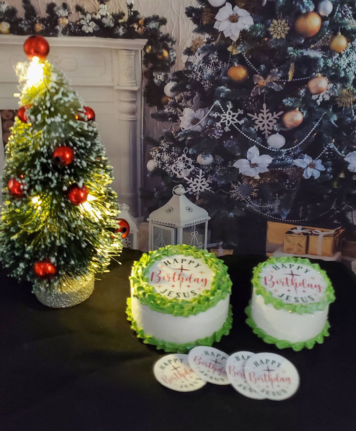 Two birthday cakes with 'Happy Birthday Jesus' text in front of a decorated Christmas tree.
