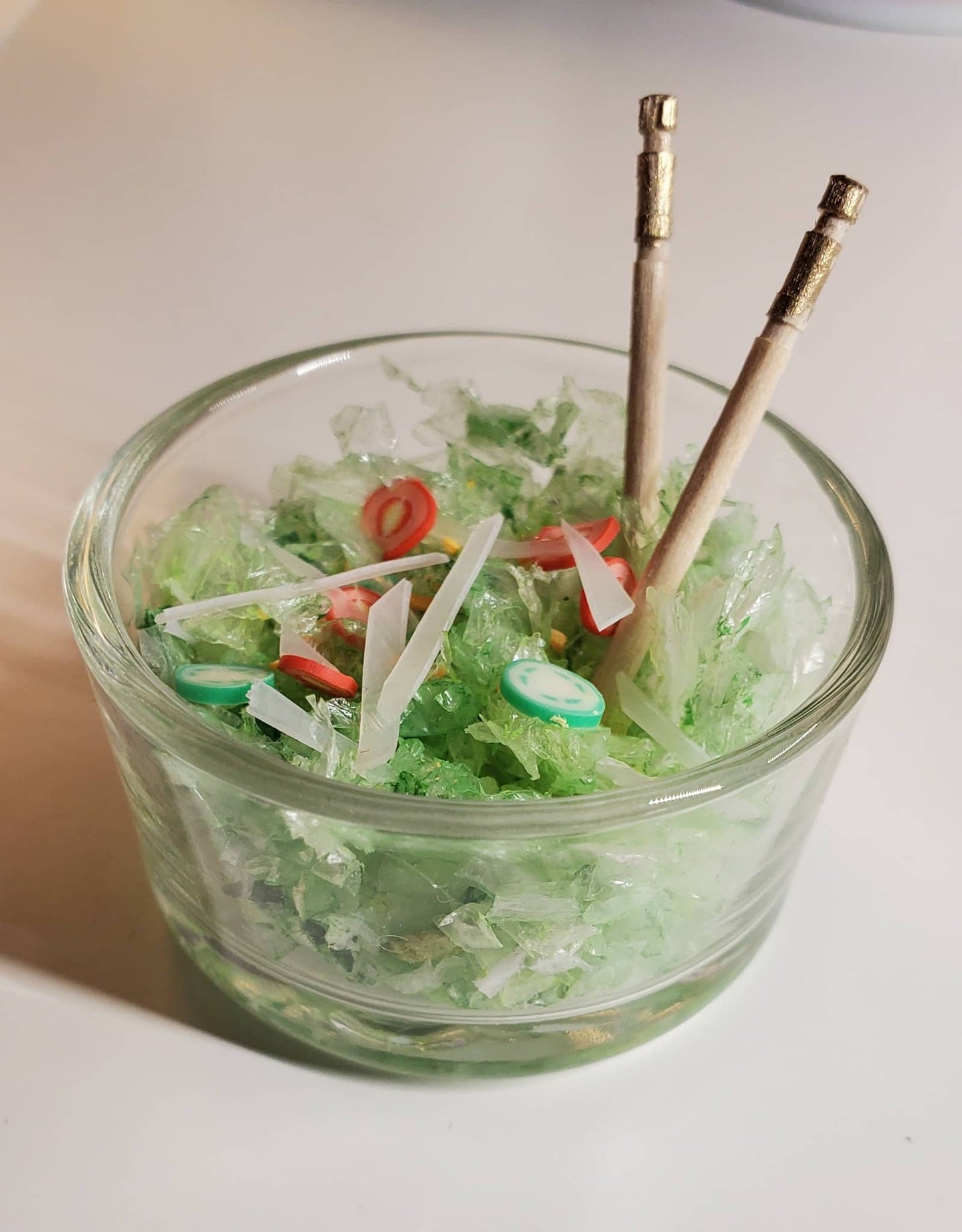 Clear glass bowl with green contents and skewers on a white background