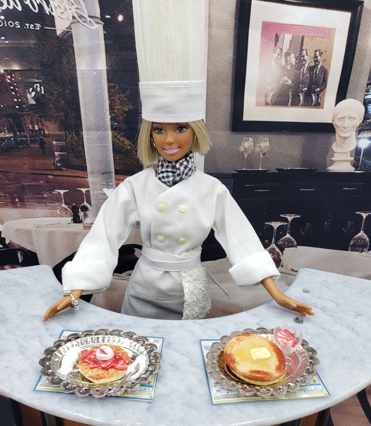 Chef Gina's tiny pancakes for dolls served on silver plates with butter and syrup beside a doll chef in white uniform