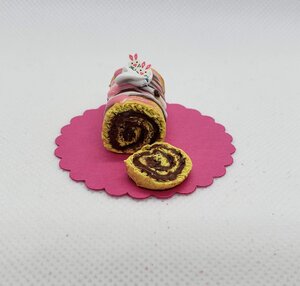 Miniature Easter Swiss roll cake with chocolate filling and colorful frosting on a pink stand