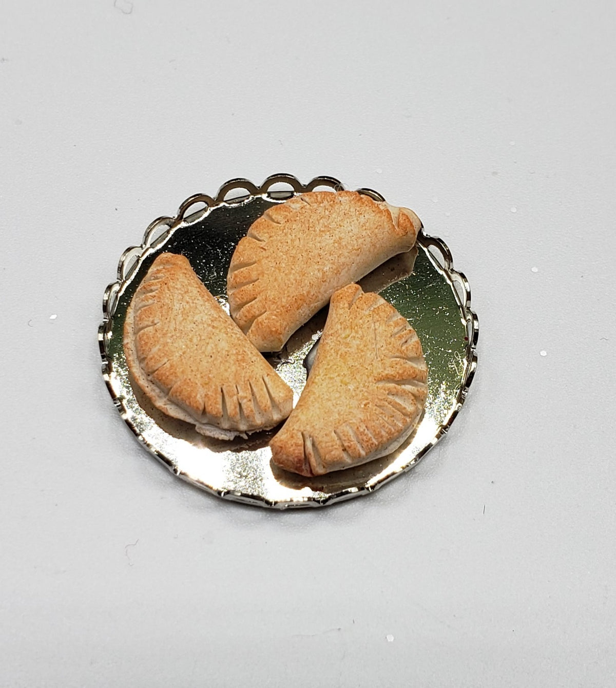 Miniature pierogi for dolls displayed on a silver plate for dollhouse dining