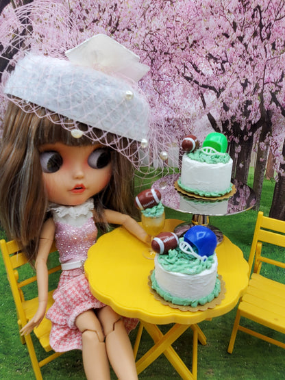 1:6 scale doll football drinks with miniature football-themed cakes on yellow table outdoors