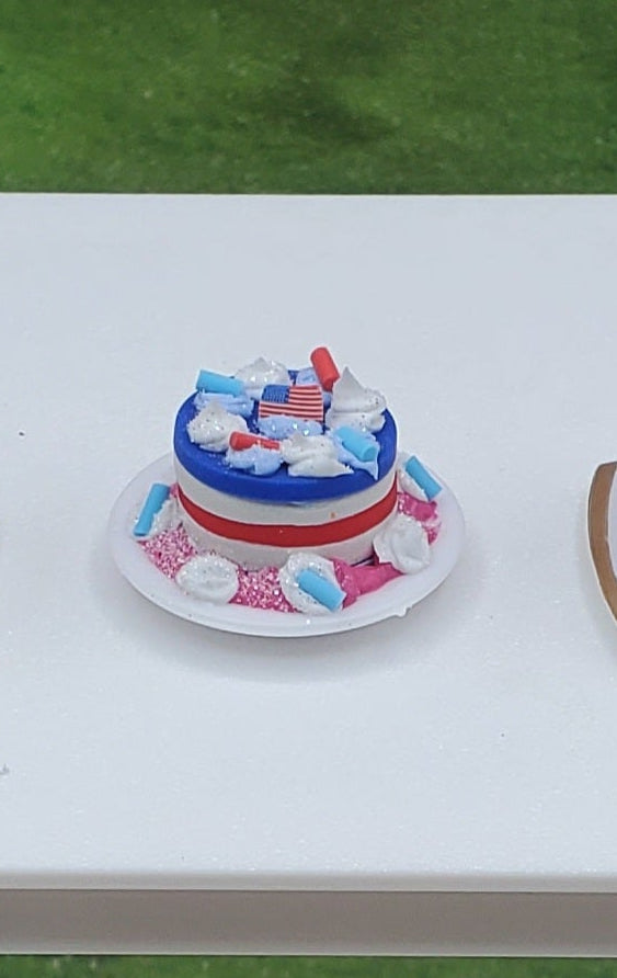 Five small decorated cakes on a table outdoors with grass and trees in the background