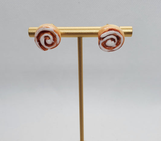 Chef Gina's Mini Food miniature cinnamon roll earrings displayed on a gold stand