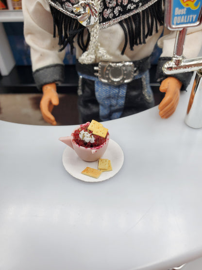 Cup of Chili with Crackers For Dolls by Chef Gina's Mini Food displayed on a white plate with a doll in the background