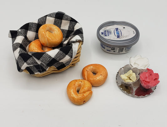 Miniature bagel basket with small bagels, cream cheese container, and butter and jam spreads for breakfast