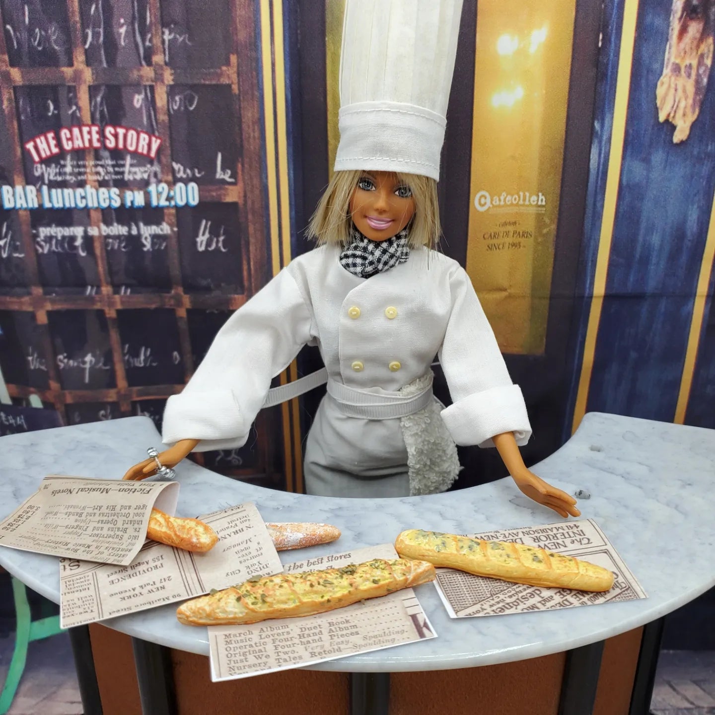 Chef Gina's miniature baguette bread displayed on a table with a chef doll in white uniform and hat