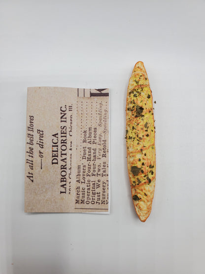 Chef Gina's miniature baguette bread with herbs and seasoning next to a Delica Laboratories Inc. label