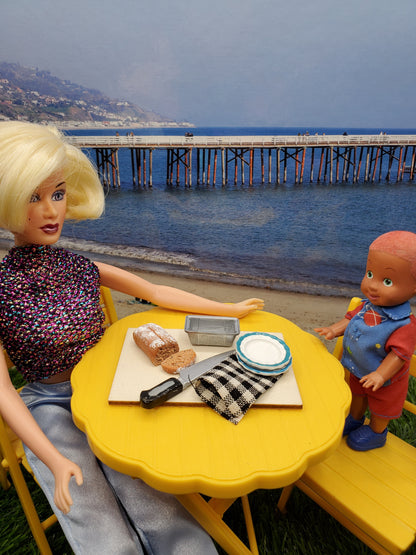 Chef Gina's miniature banana bread for dolls displayed on a picnic table by the beach