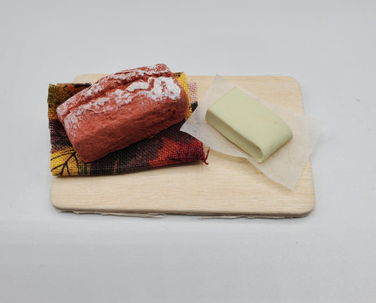 Chef Gina's miniature banana loaf for dolls with a dusting of powdered sugar on colorful cloth