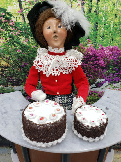 Two Miniature Blackforest Cakes decorated with cream and cherries on a table