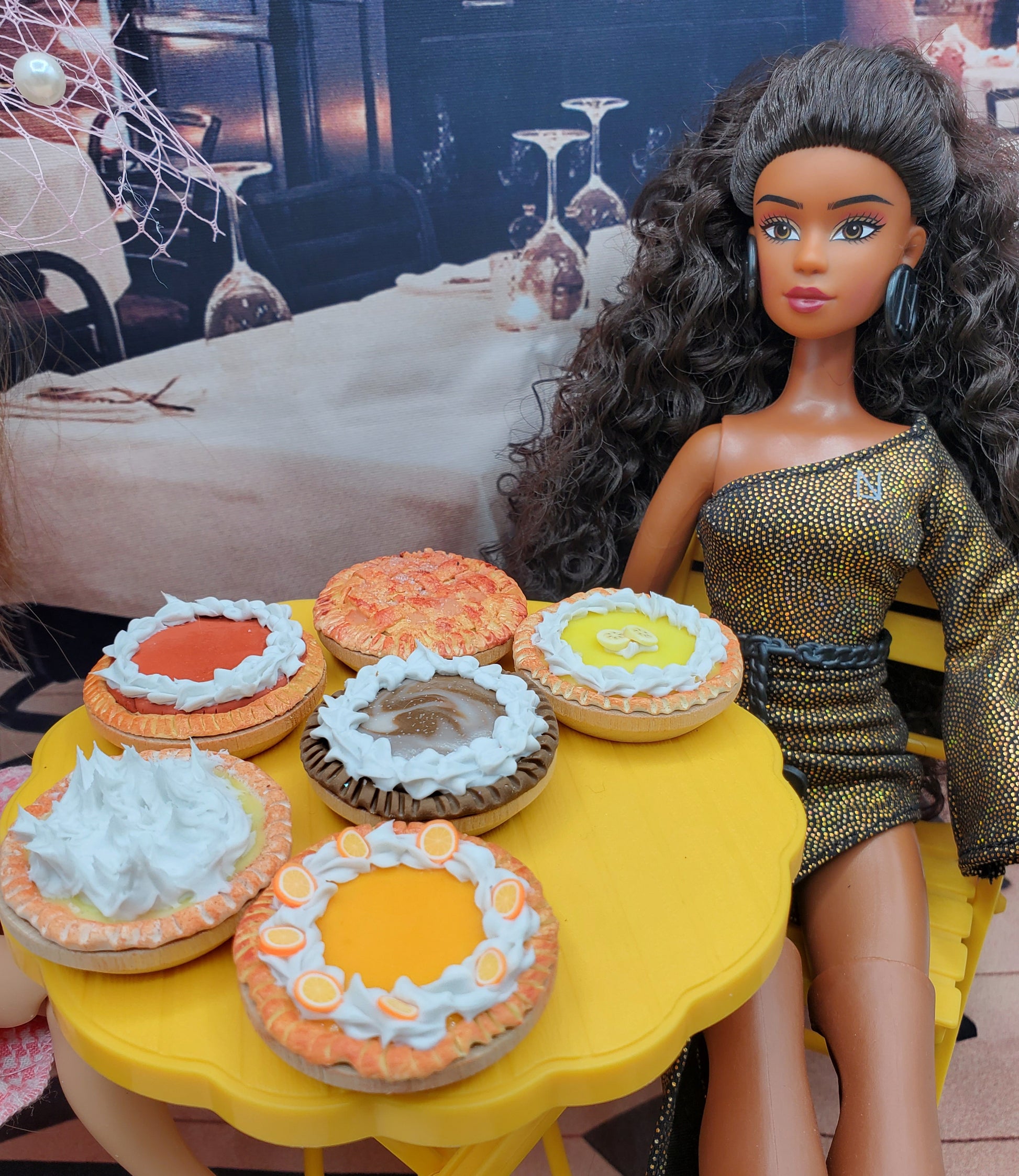 Chef Gina's miniature chocolate Oreo pie and assorted miniature pies displayed on a yellow table next to a doll