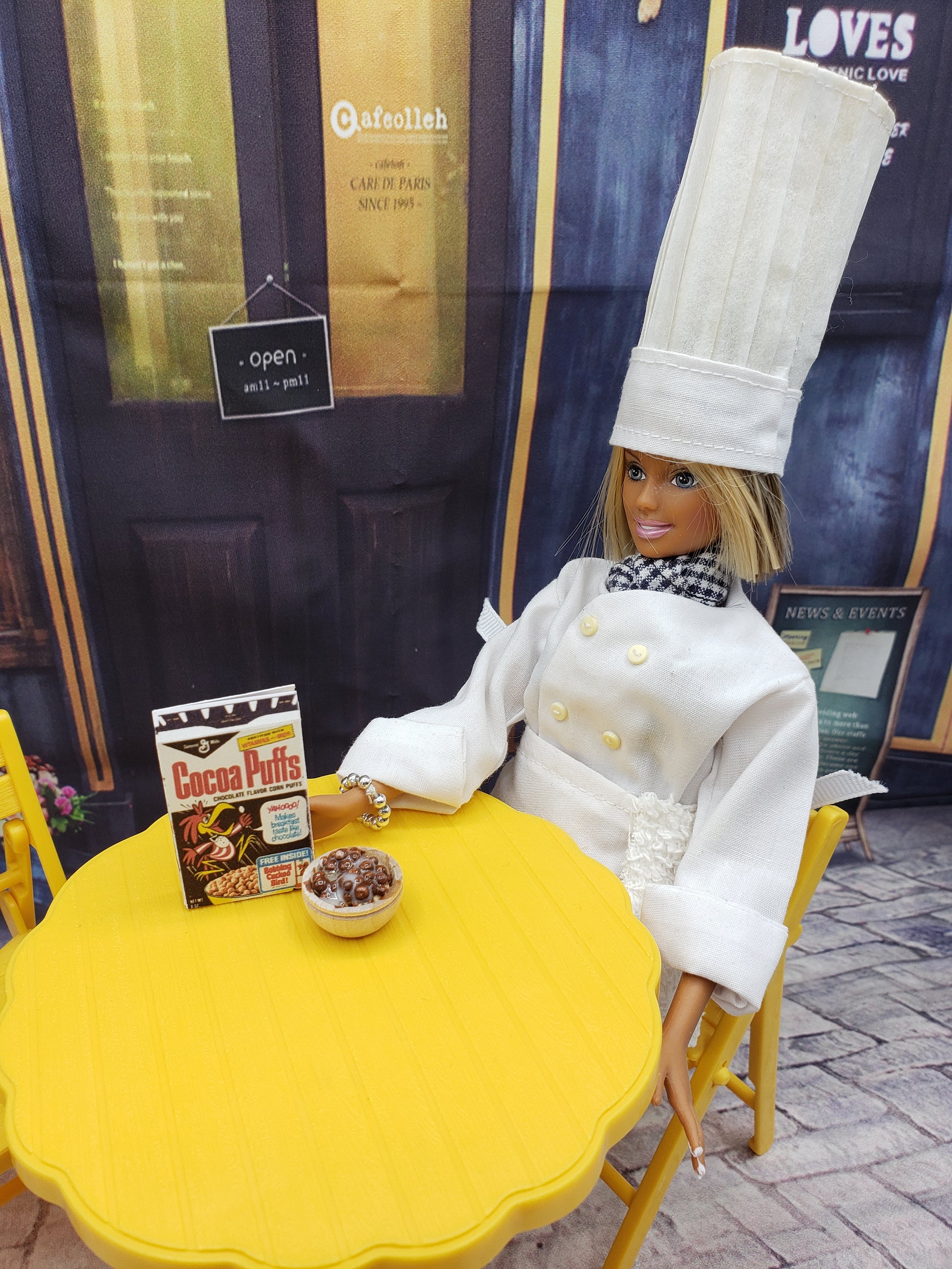Chef Gina's miniature Coco Puffs cereal for dolls with doll chef sitting at yellow table