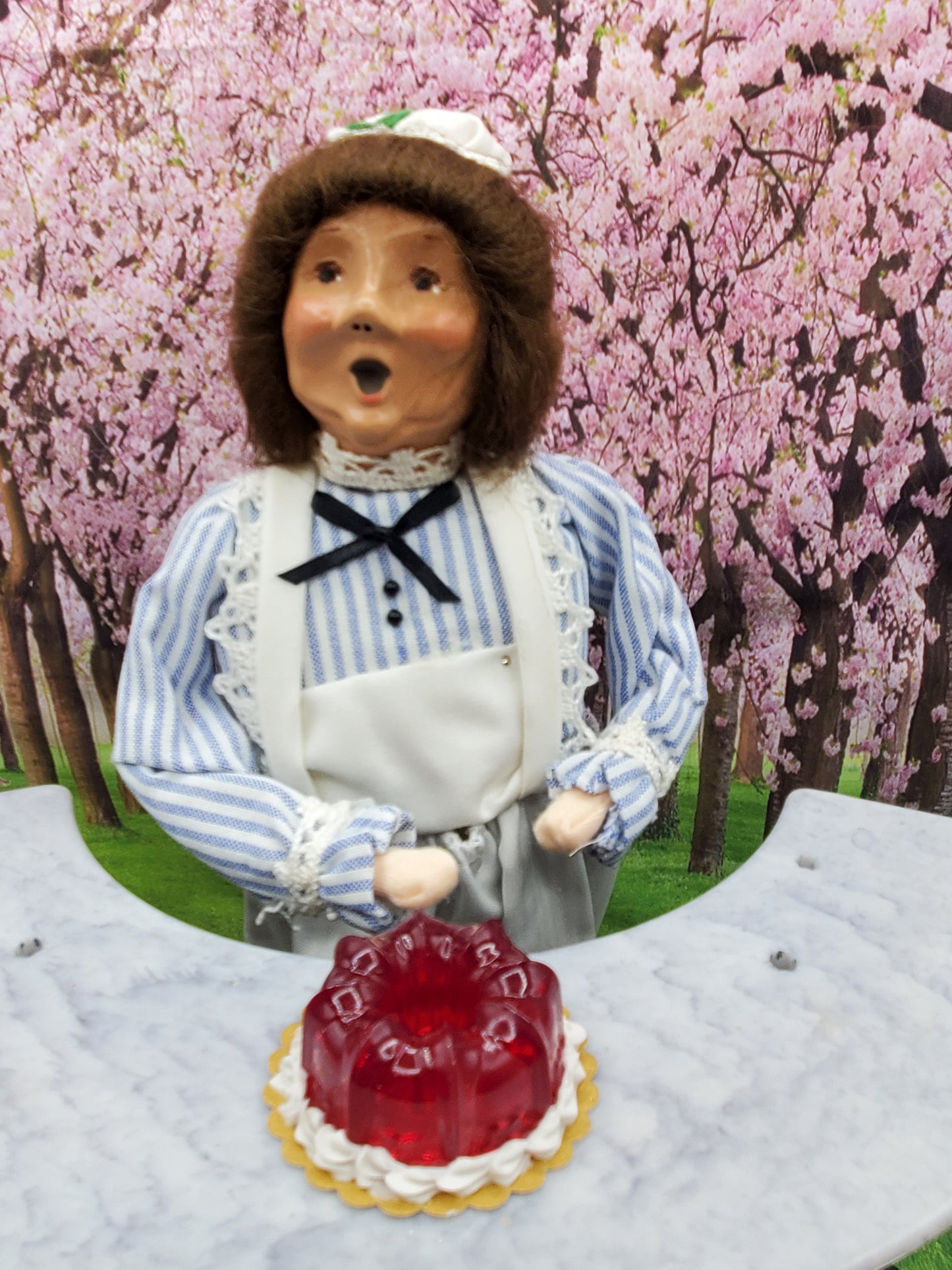 Miniature cranberry jello dessert in front of a chef doll with a striped blue shirt and apron