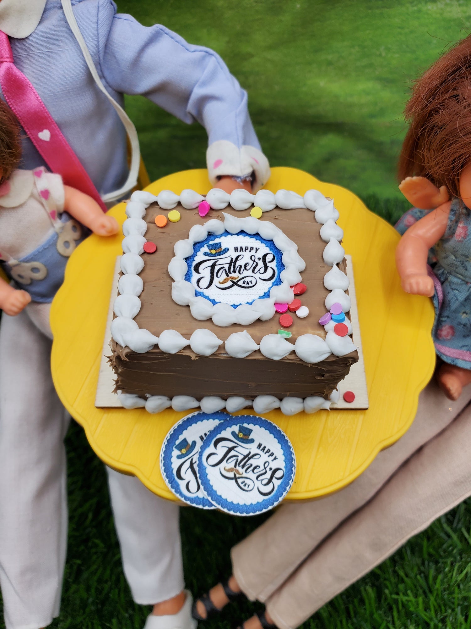 Miniature Father's Day cake with chocolate frosting and festive decorations on a yellow cake stand