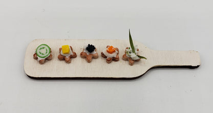 Chef Gina's miniature hors d'oeuvres platter with five assorted bite-sized appetizers on a wooden paddle