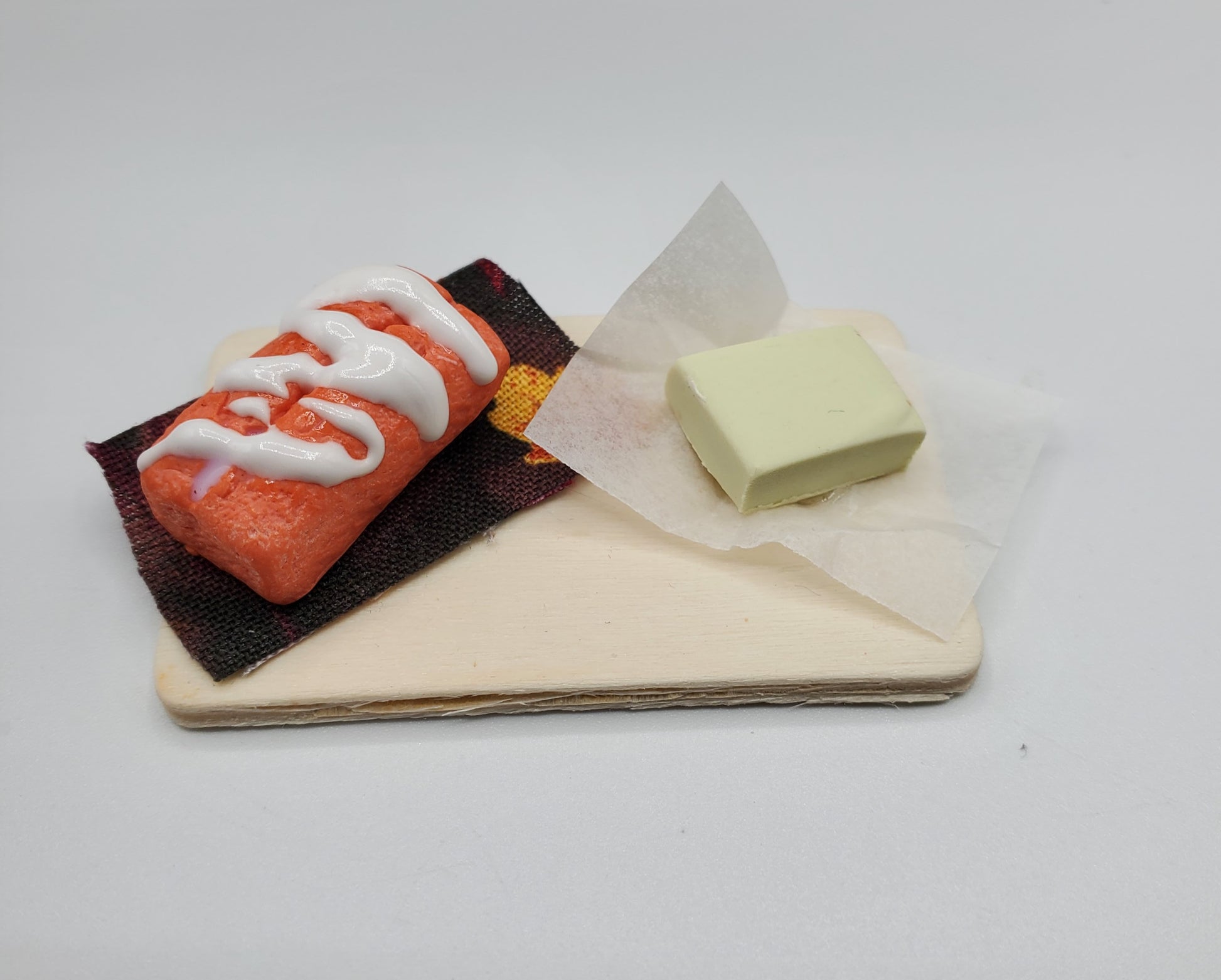 Chef Gina's miniature orange cream bread dessert with white icing on a small wooden board