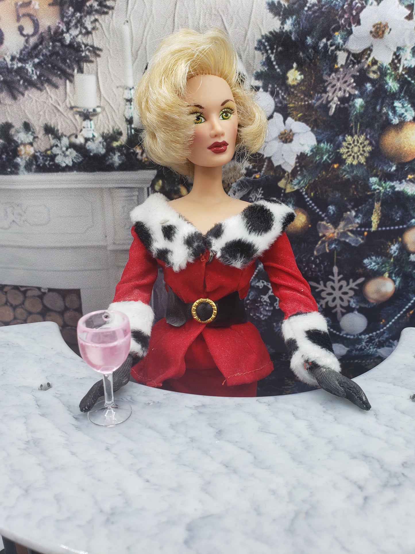 Fashion doll dressed in red holiday outfit holding a miniature rose wine for fashion dolls on marble table