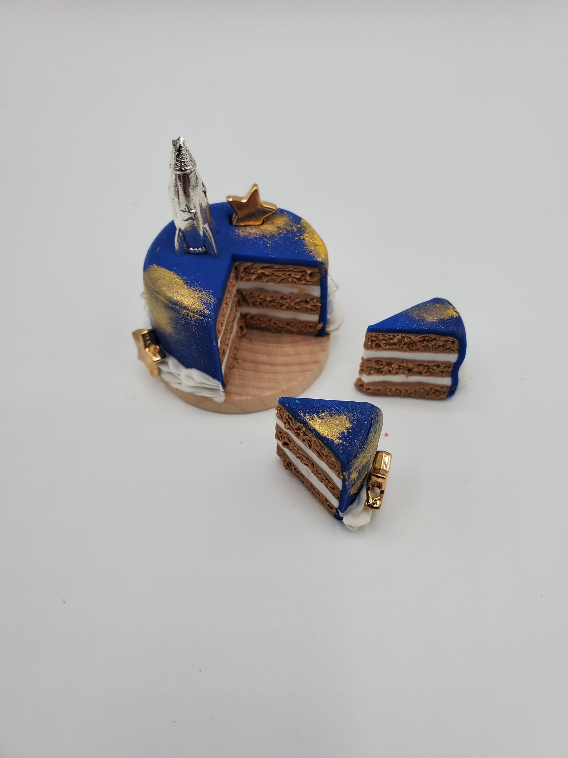 Miniature space cake for dolls with blue and gold outer space design and silver rocket on top