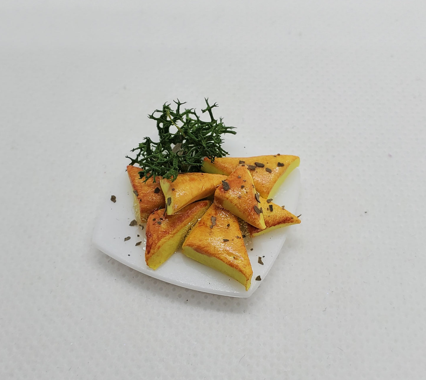 Miniature spanakopita fashion dolls on a white plate with herbs for detailed display