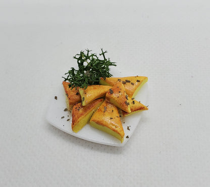 Miniature spanakopita fashion dolls on a white plate with herbs for detailed display