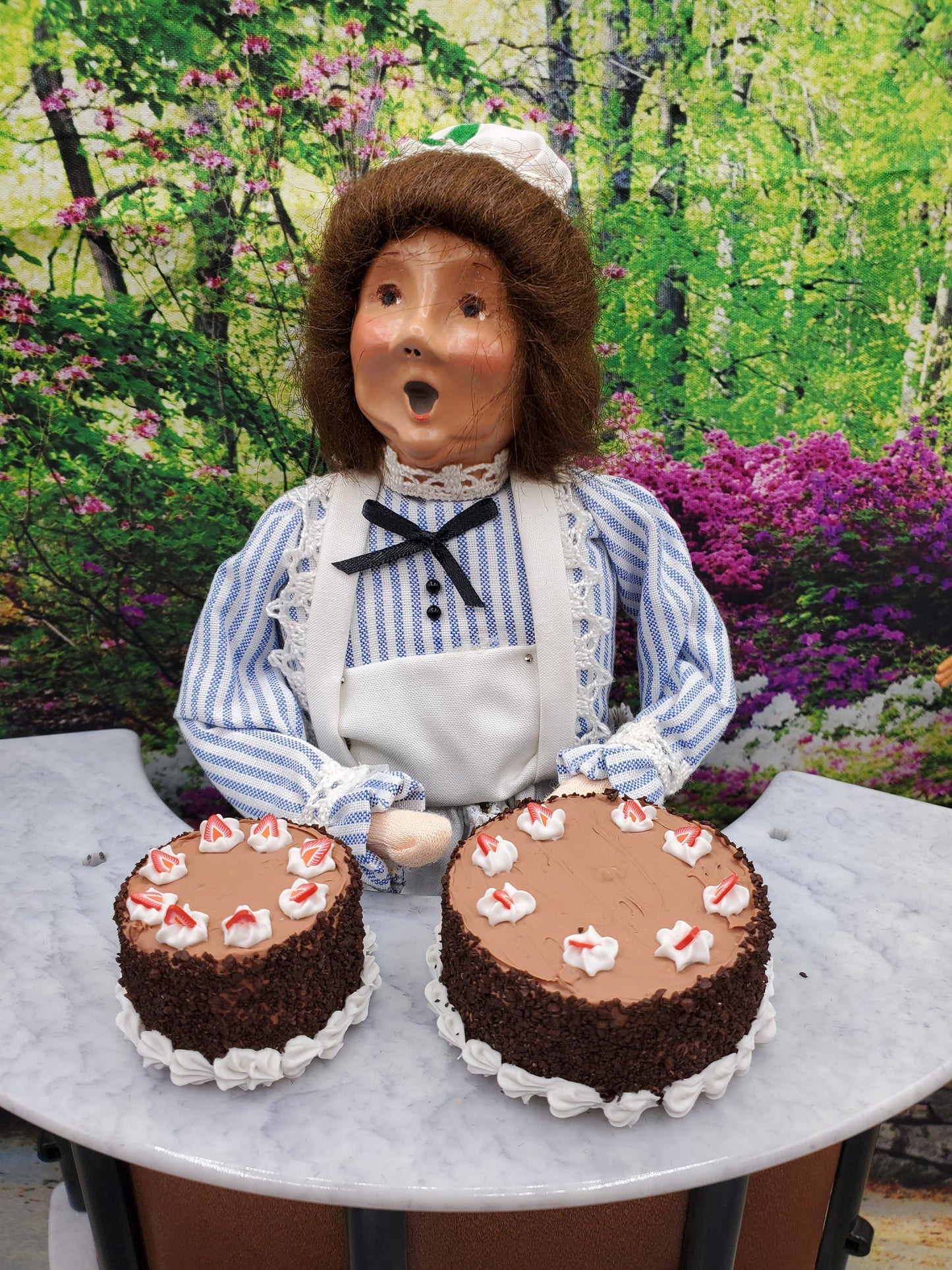 Chef Gina presenting two miniature spring chocolate cakes decorated with icing and fresh fruit