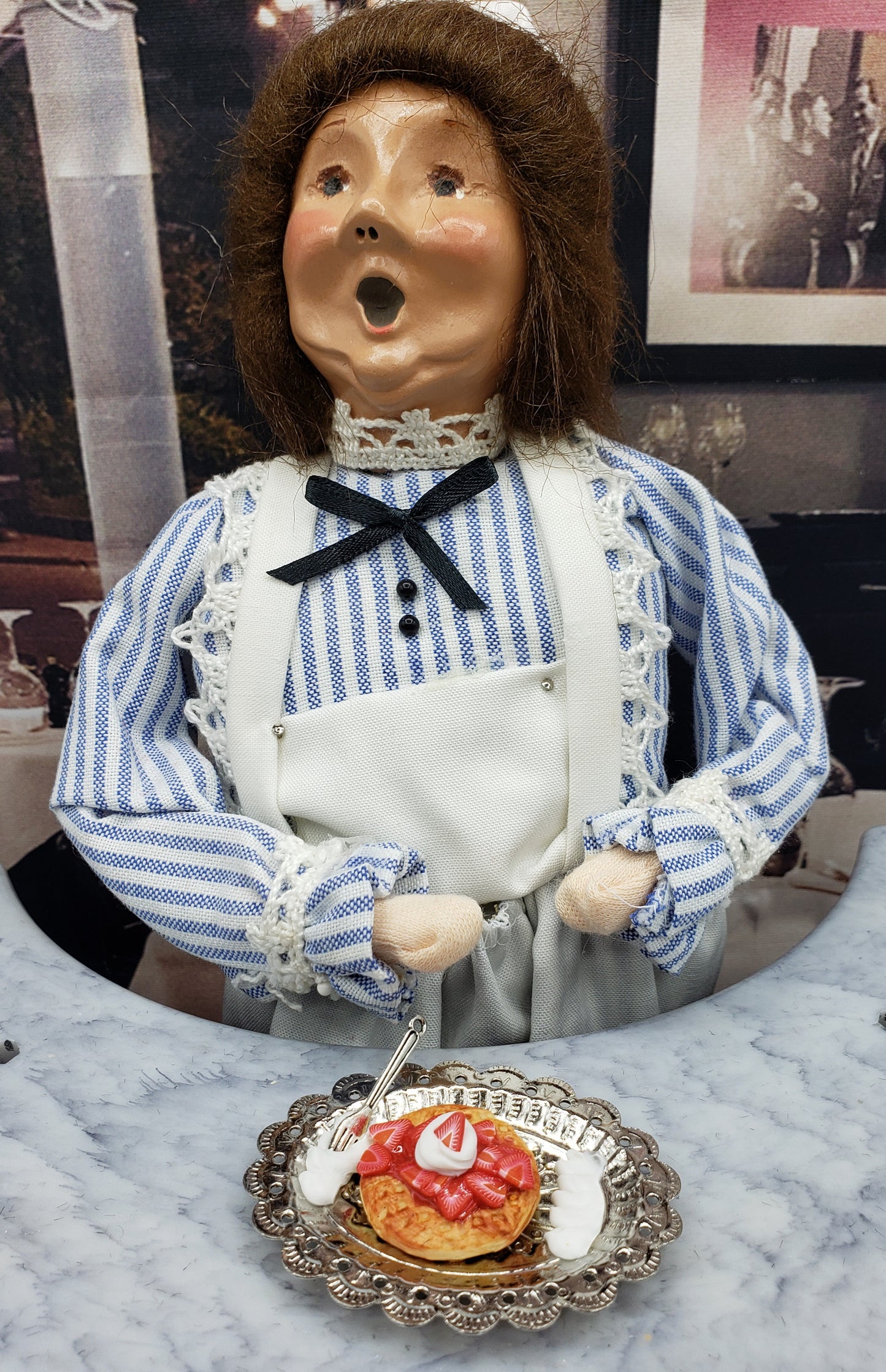 Miniature strawberry waffle for dolls served on a silver plate with a fork, displayed in front of a doll in vintage clothing