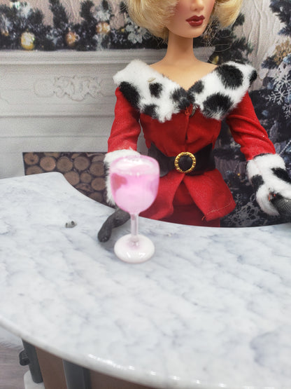 One sixth scale party punch in a clear glass held by a doll dressed in red with black and white fur details