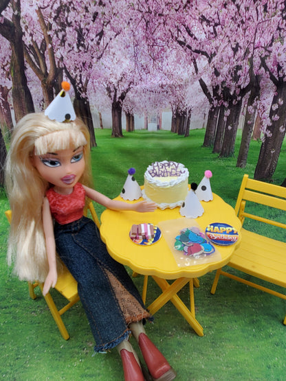 Chef Gina's Mini Food pink flamingo doll party set with doll, birthday cake, cookies, and party hats on yellow table