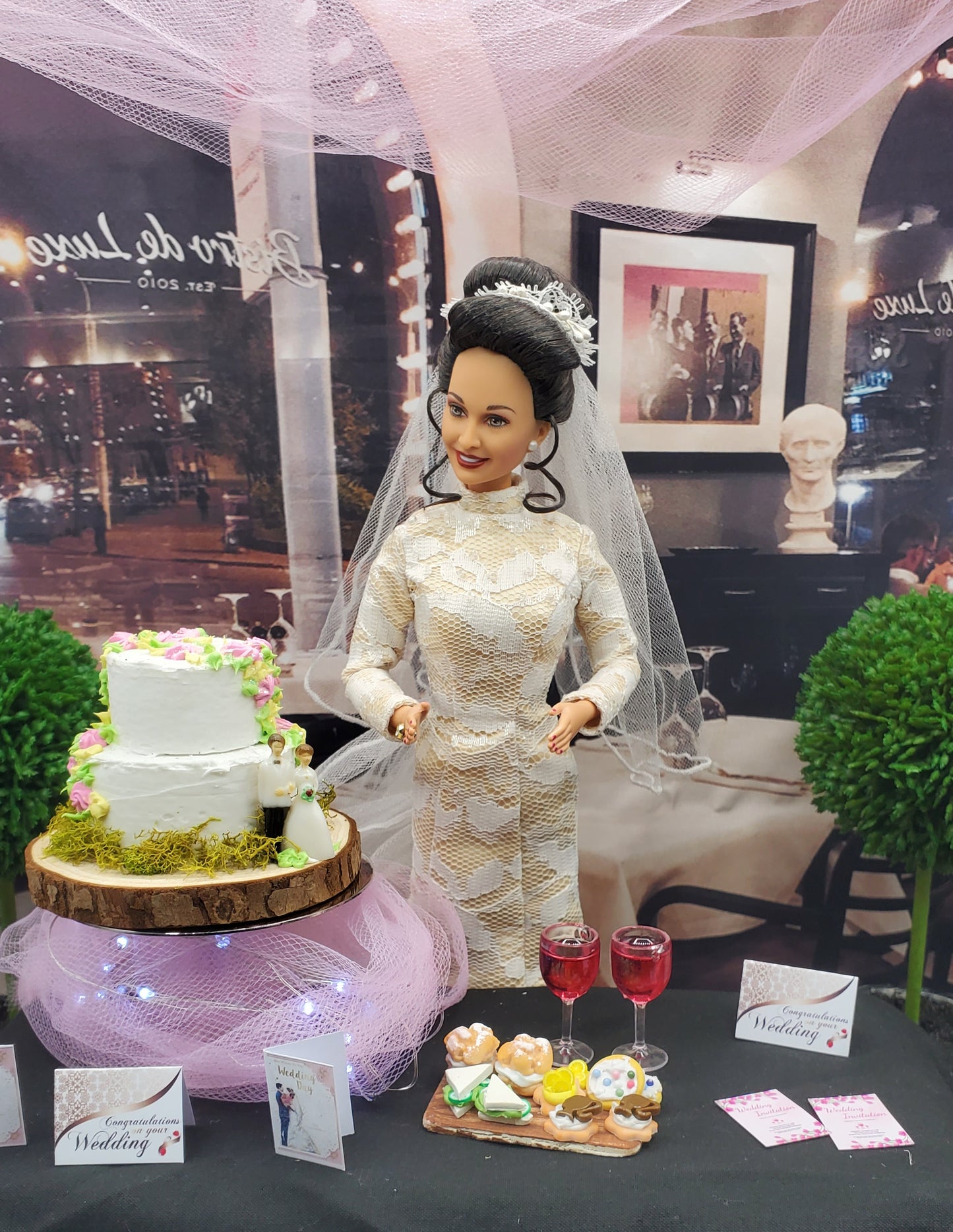 Barbie doll in a wedding dress with a cake and flowers on a table.