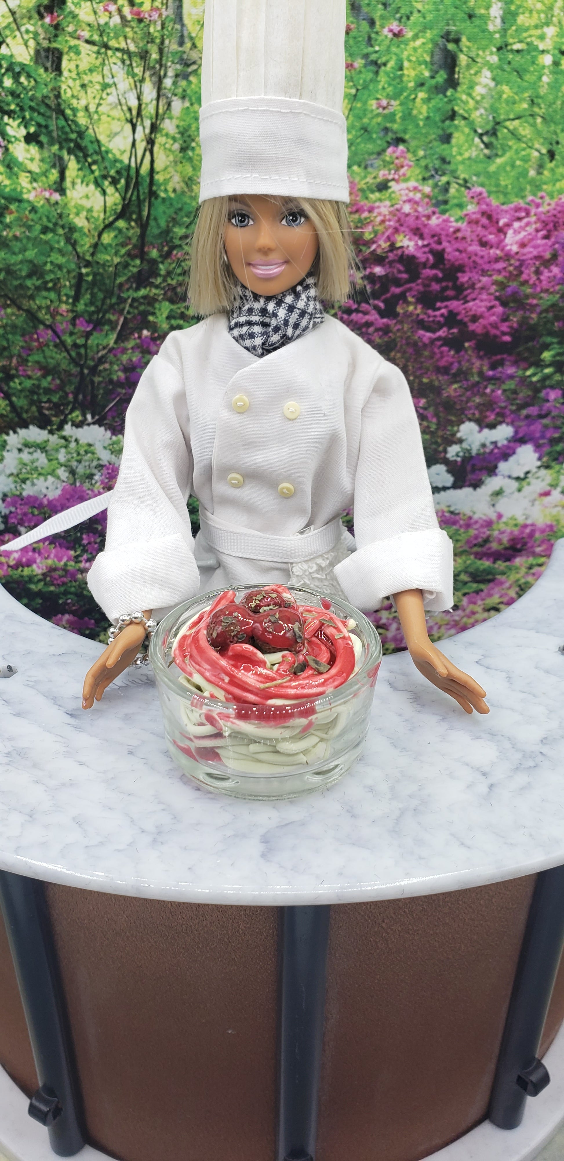 Chef doll dressed in white uniform with 1:4th scale Spaghetti and Meatballs for dolls in a glass bowl on marble table