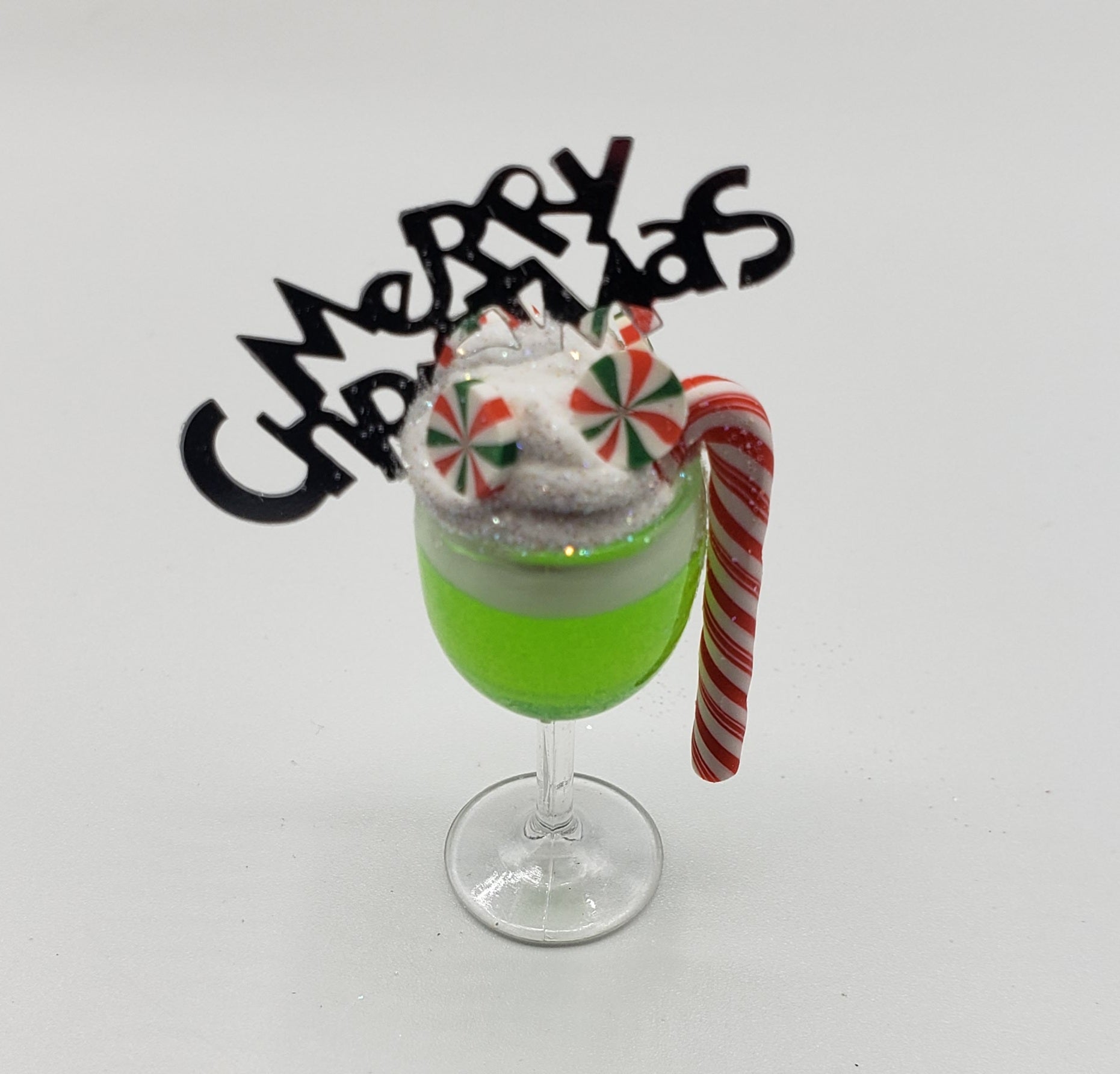 Chef Gina's miniature Christmas drink with green beverage, candy cane, peppermint candies, and Merry Christmas sign