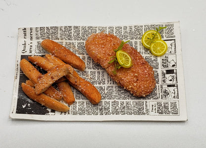 Miniature fried fish for dolls served with fries and lemon slices on a newspaper plate