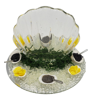 Miniature ice carving sculpture with lemon decor and caviar serving bowls on a glass platter