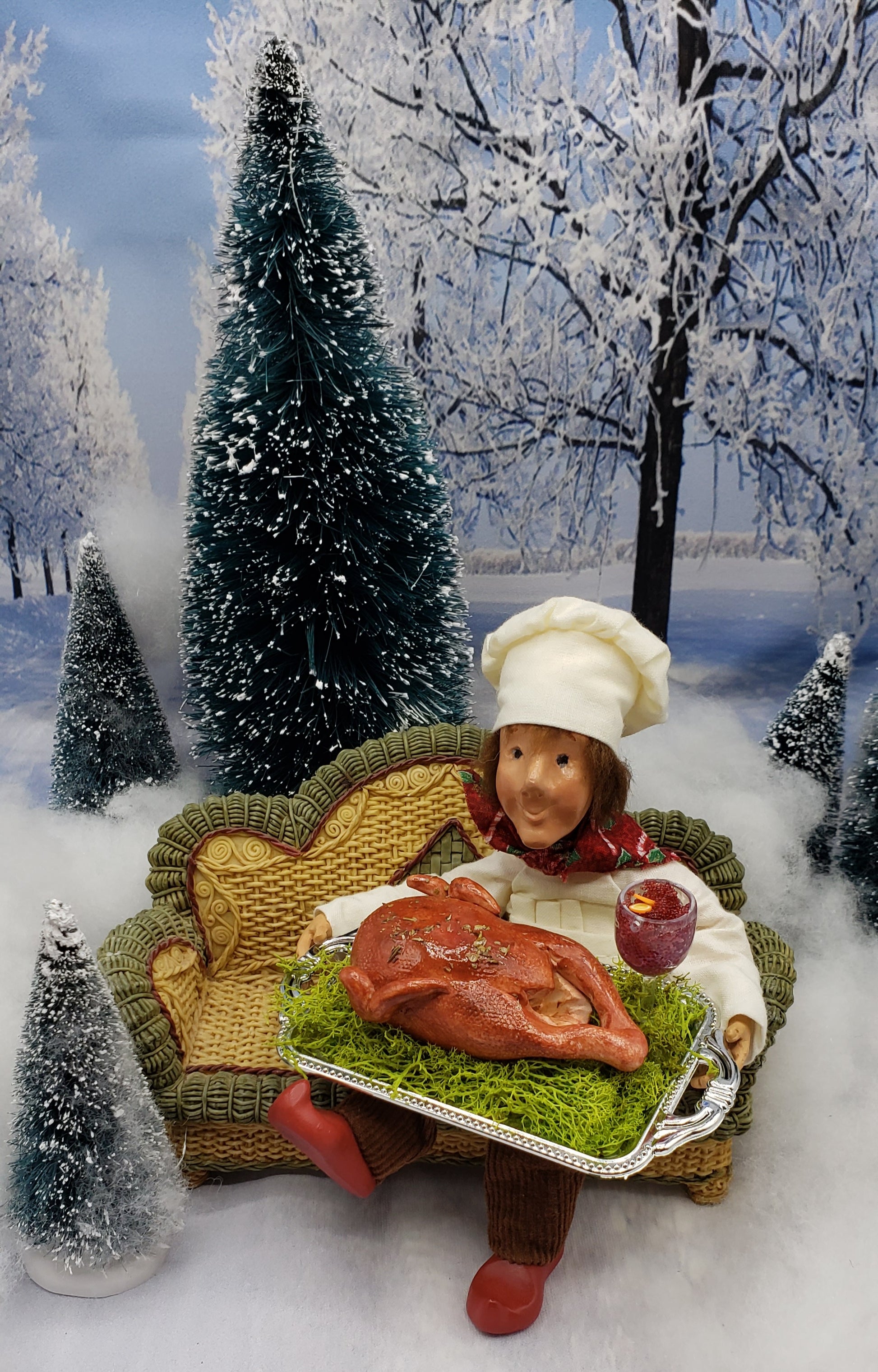 Chef Gina's miniature turkey platter for dolls held by a chef doll on a wicker couch in a snowy winter scene